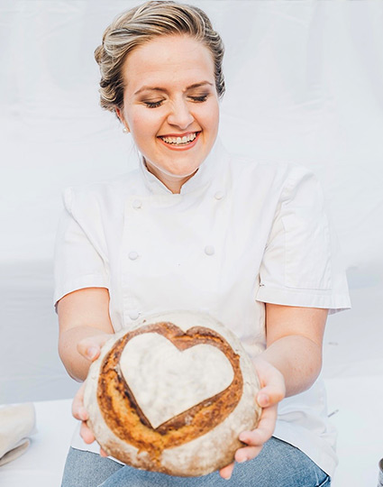 Lachende Frau mit einem Laib Brot in der Hand