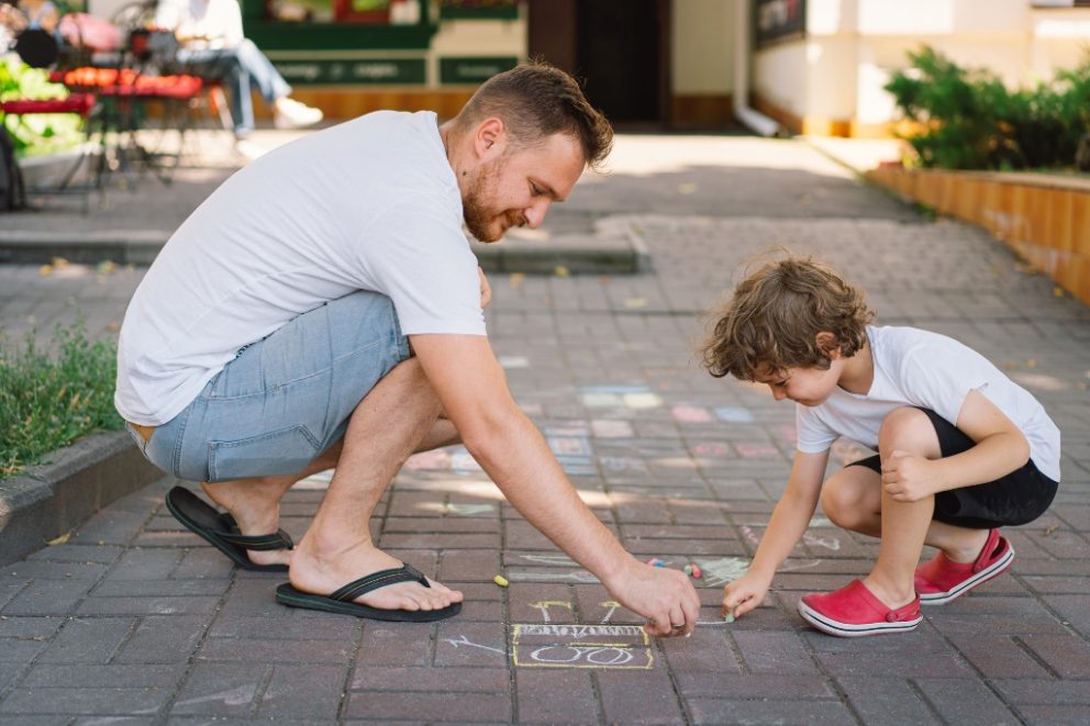 Vater und Kind malen ein Straßenbild